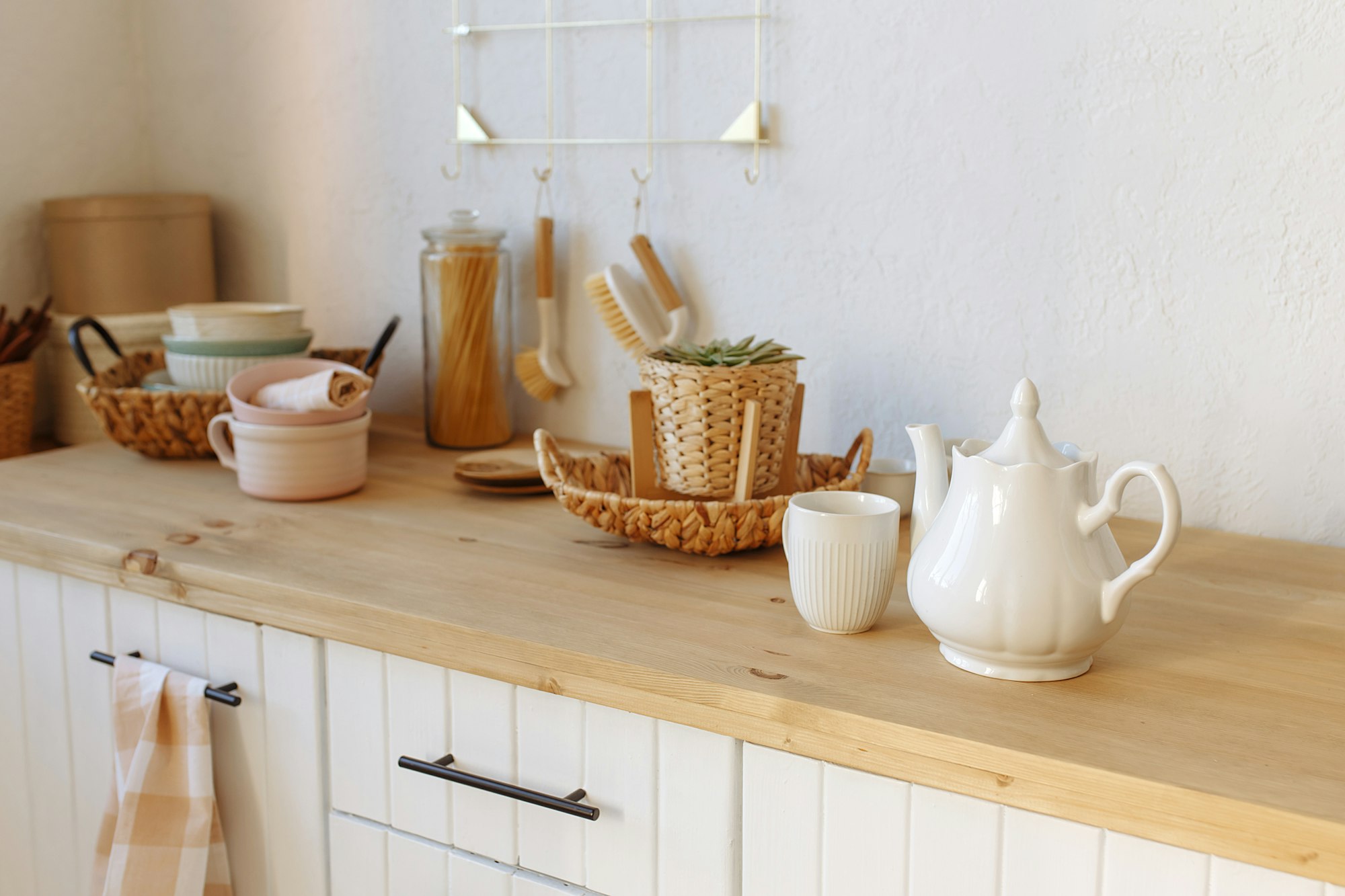 White cup of tea with a teapot on the background of the kitchen interior.