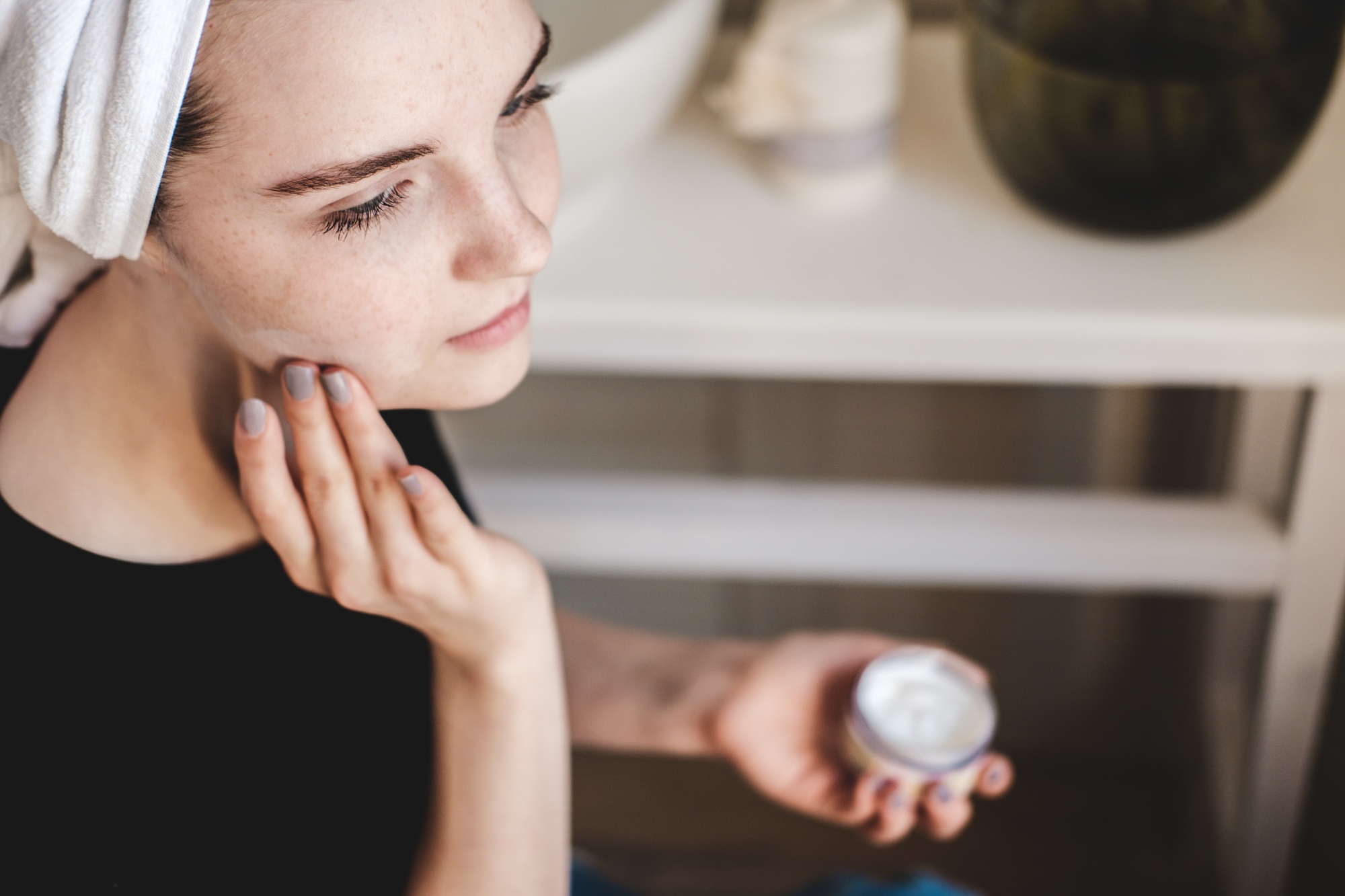 Beautiful young woman applied cream on her skin. Morning routine. Skincare.