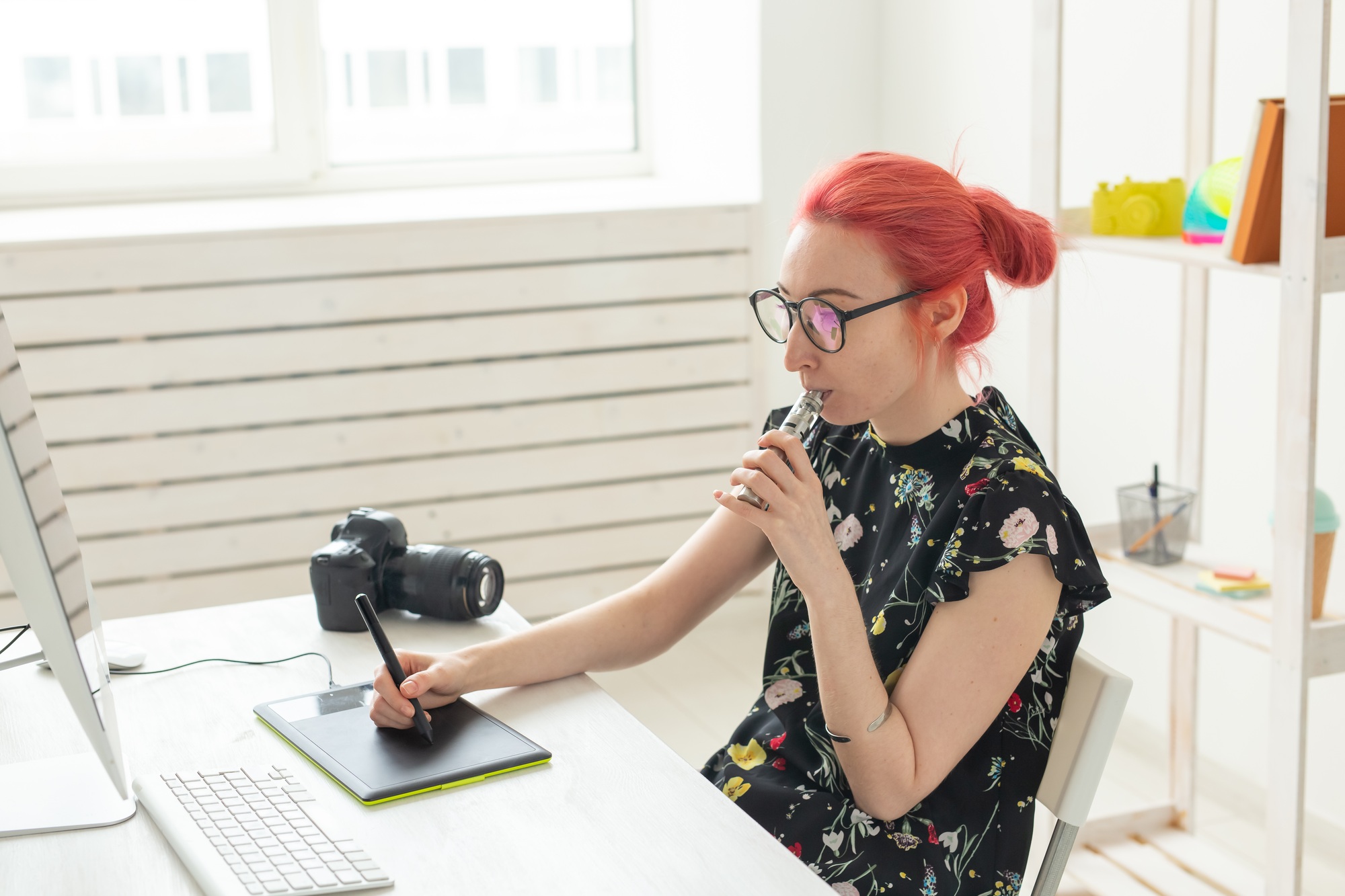 Creative, graphic designer, people concept - young creative woman smoking a vape while working in a